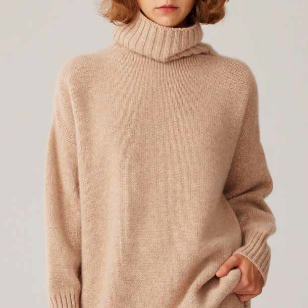 Person wearing a beige turtleneck sweater against a plain background